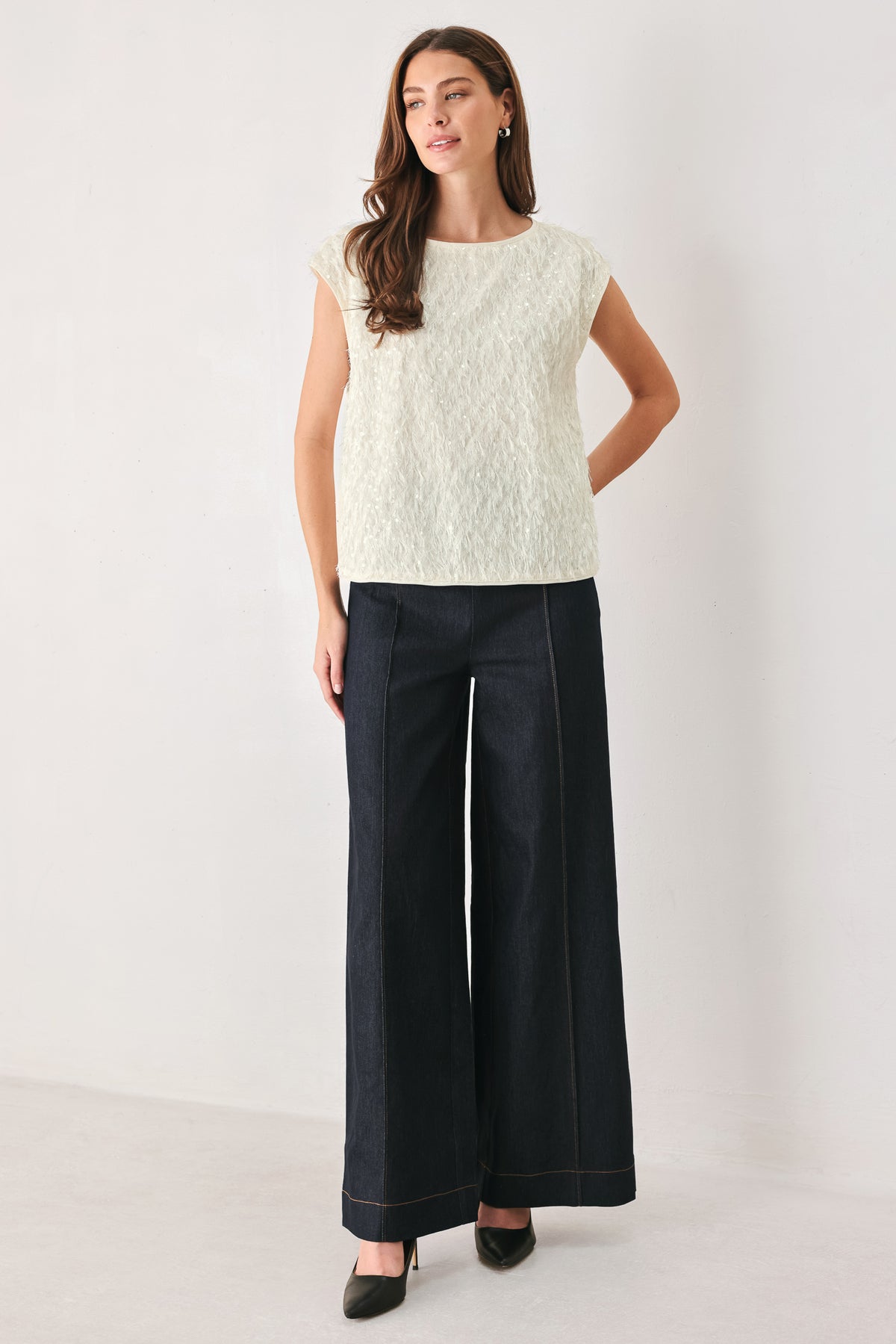 Woman wearing an off white cap sleeve. boat neck mid length top with sequin and light feather texture | FREEMARKET