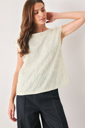 Woman wearing an off white cap sleeve. boat neck mid length top with sequin and light feather texture | FREEMARKET