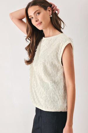 Woman wearing an off white cap sleeve. boat neck mid length top with sequin and light feather texture | FREEMARKET