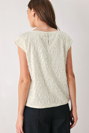 Woman wearing an off white cap sleeve. boat neck mid length top with sequin and light feather texture | FREEMARKET