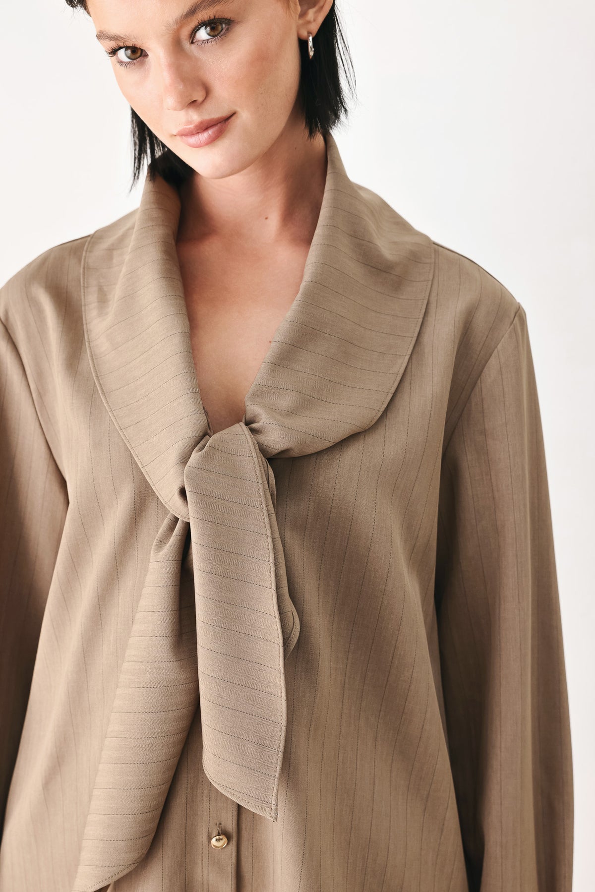 A woman wearing a taupe-beige long-sleeve button-front blouse with a large draped collar | FREEMARKET
