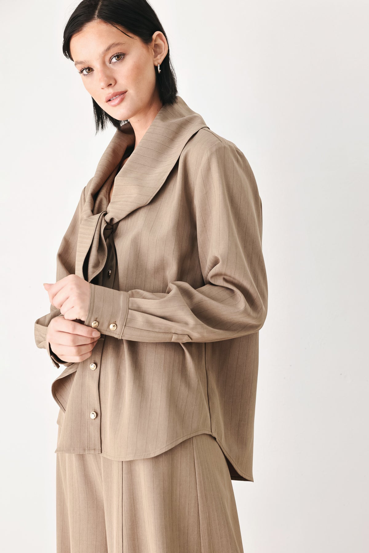 A woman wearing a taupe-beige long-sleeve button-front blouse with a large draped collar | FREEMARKET
