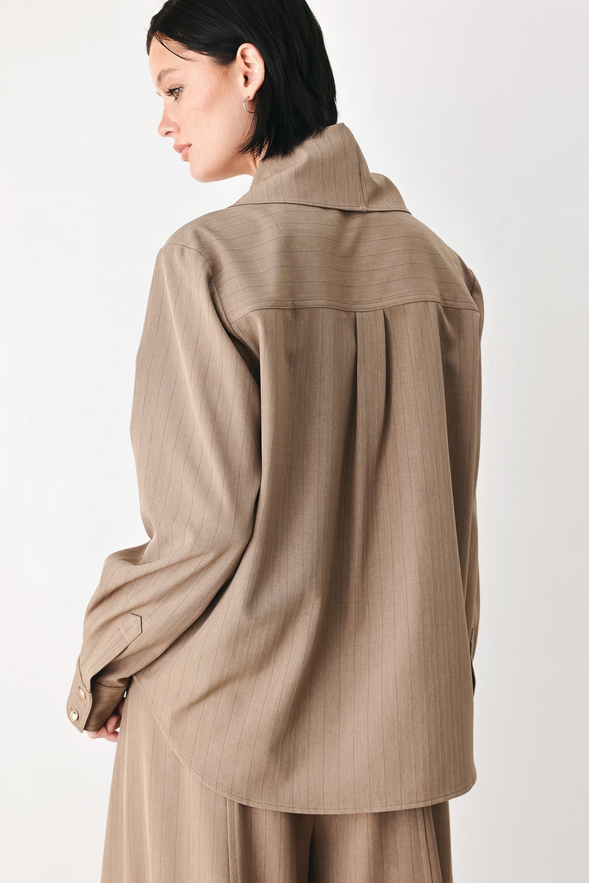 A woman wearing a taupe-beige long-sleeve button-front blouse with a large draped collar | FREEMARKET