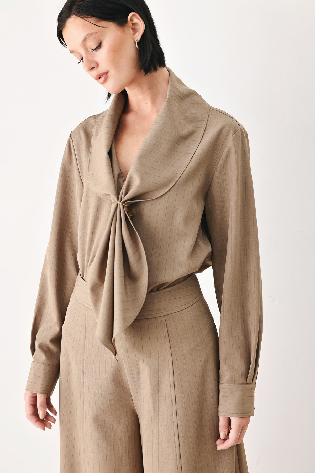 A woman wearing a taupe-beige long-sleeve button-front blouse with a large draped collar | FREEMARKET