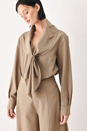 A woman wearing a taupe-beige long-sleeve button-front blouse with a large draped collar | FREEMARKET