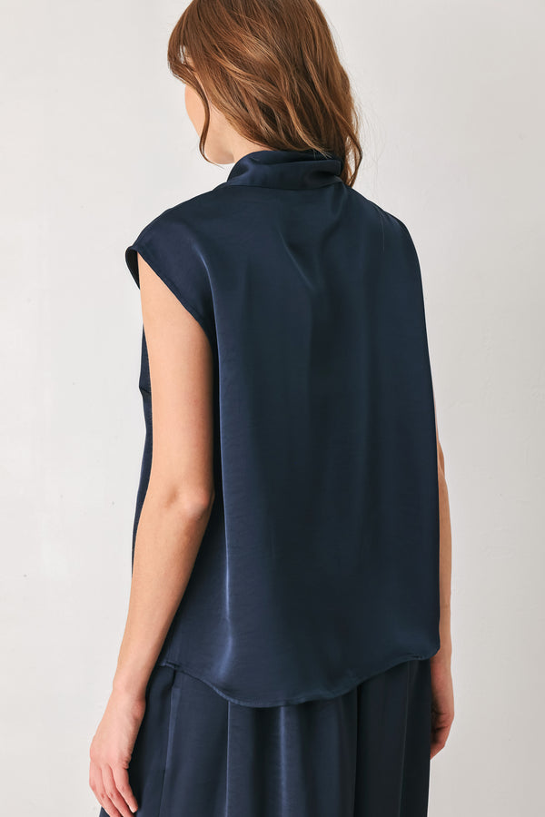 Woman wearing a navy blue cap sleeve satin top with a bow along the neck | FREEMARKET