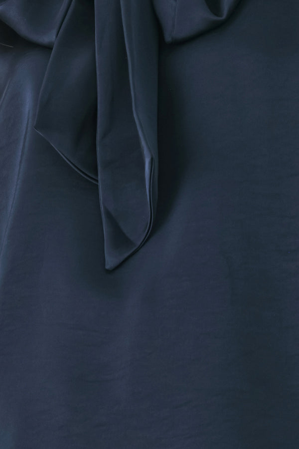 Woman wearing a navy blue cap sleeve satin top with a bow along the neck | FREEMARKET