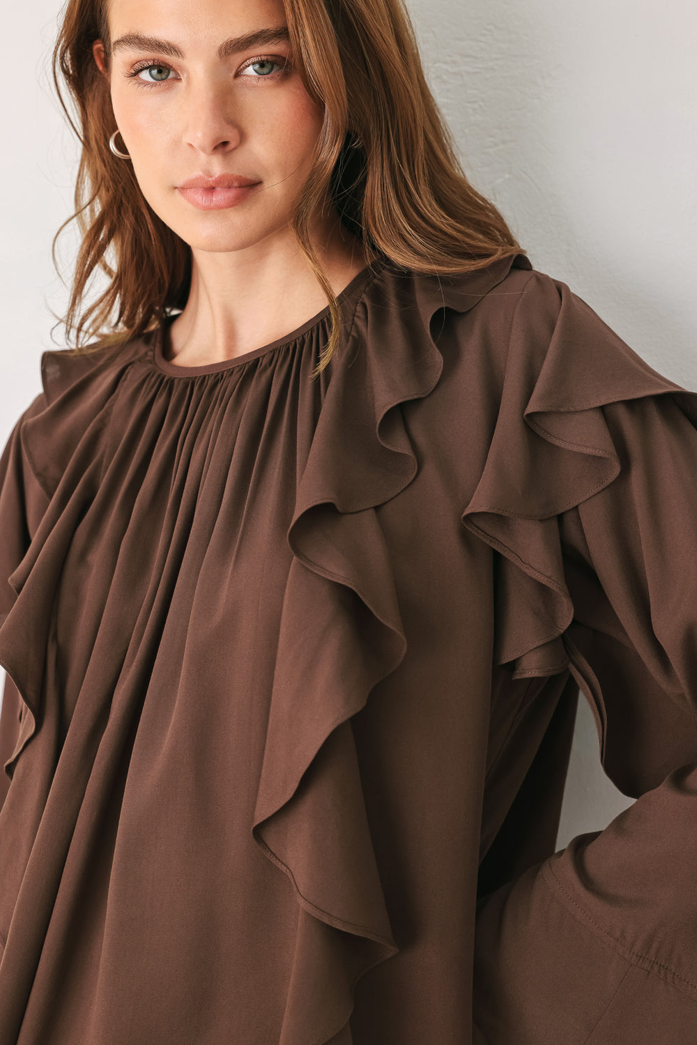 Woman wearing a long sleeve brown top with ruffles | FREEMARKET