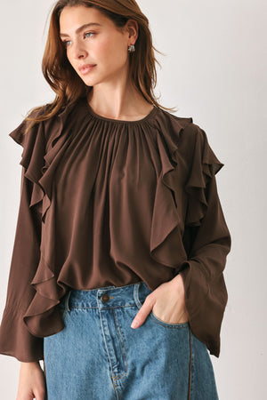 Woman wearing a long sleeve brown top with ruffles | FREEMARKET