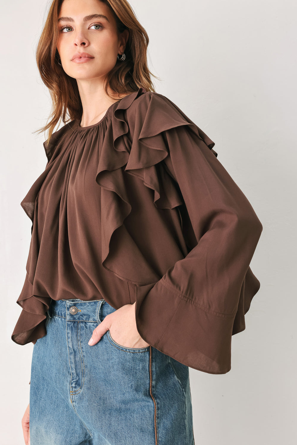 Woman wearing a long sleeve brown top with ruffles | FREEMARKET