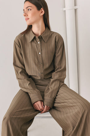 Woman wearing a brown button up long sleeve top with thin vertical black lines | FREEMARKET