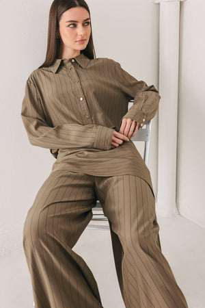 Woman wearing a brown button up long sleeve top with thin vertical black lines | FREEMARKET
