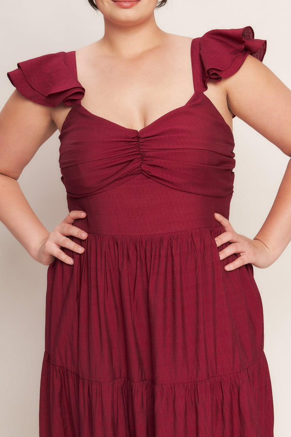 A solid woven maxi dress featuring cami top with layered sleeve, cinched front bodice, tiered skirt and smocked back bodice. FLYING TOMATO