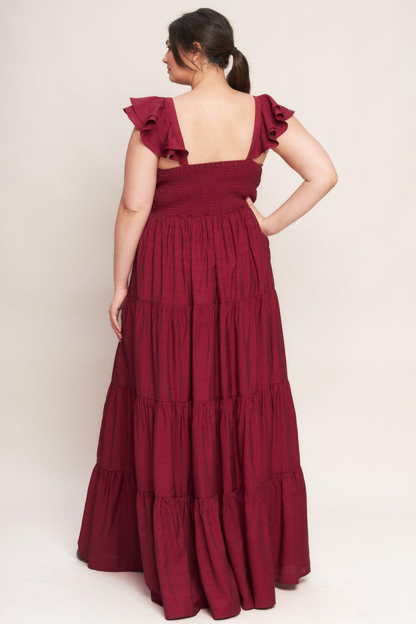 A solid woven maxi dress featuring cami top with layered sleeve, cinched front bodice, tiered skirt and smocked back bodice. FLYING TOMATO
