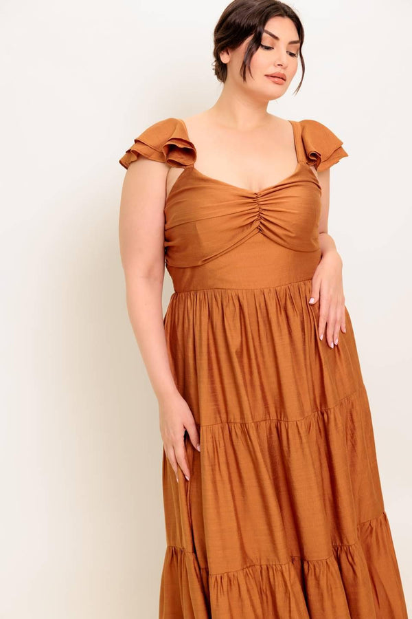 A solid woven maxi dress featuring cami top with layered sleeve, cinched front bodice, tiered skirt and smocked back bodice.