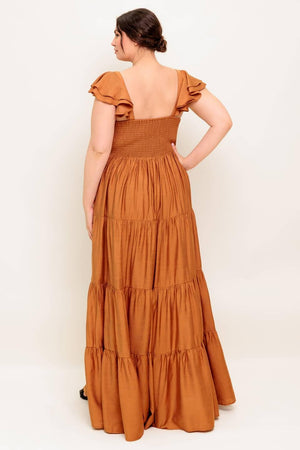 A solid woven maxi dress featuring cami top with layered sleeve, cinched front bodice, tiered skirt and smocked back bodice.