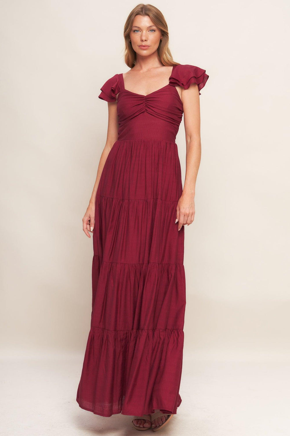 A solid woven maxi dress featuring cami top with layered sleeve, cinched front bodice, tiered skirt and smocked back bodice. FLYING TOMATO