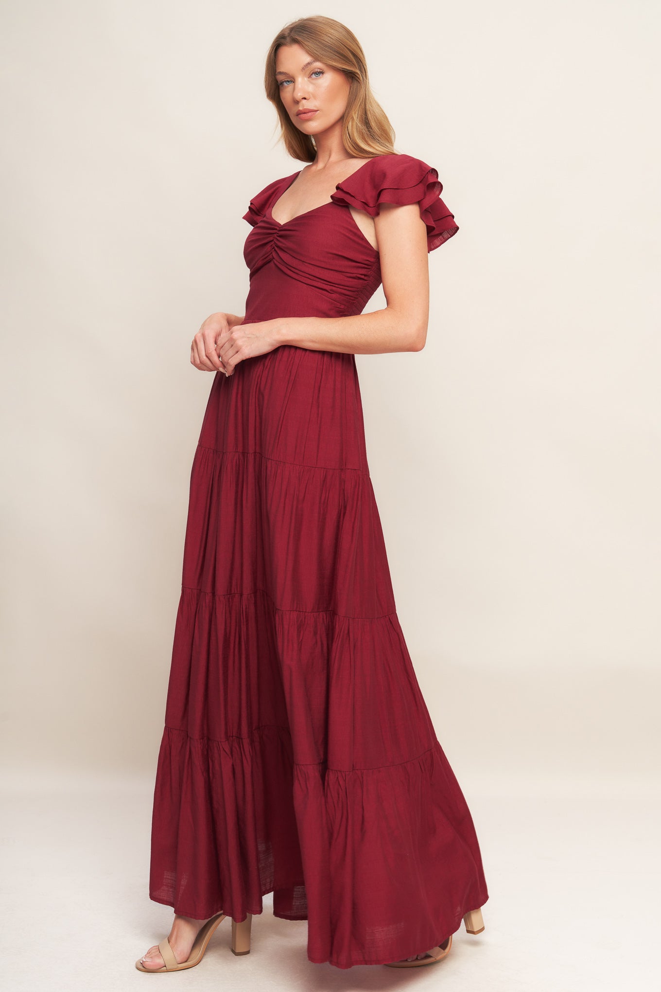 A solid woven maxi dress featuring cami top with layered sleeve, cinched front bodice, tiered skirt and smocked back bodice.