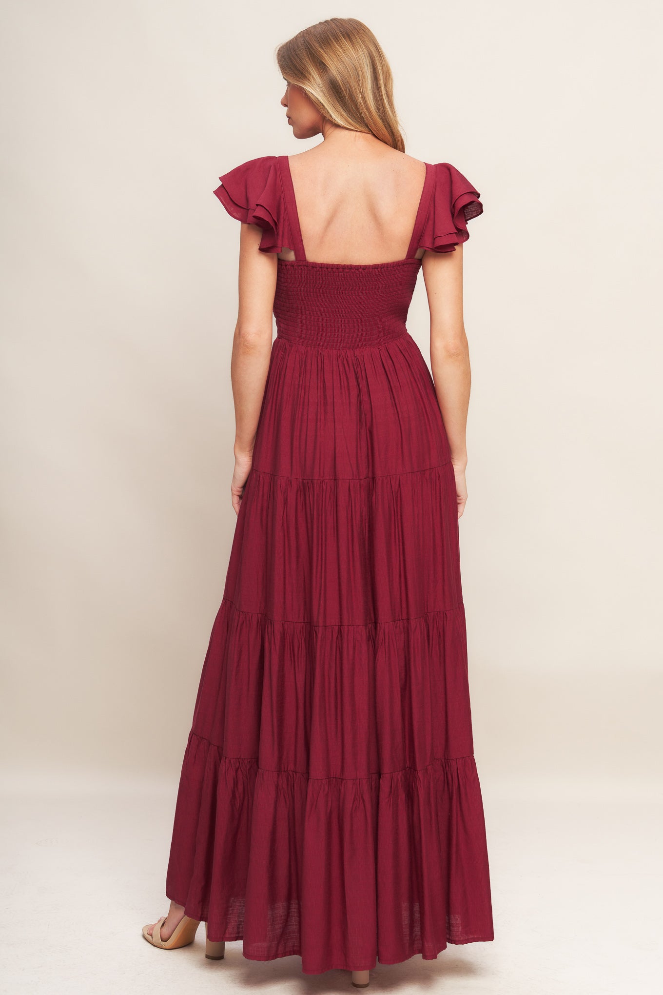 A solid woven maxi dress featuring cami top with layered sleeve, cinched front bodice, tiered skirt and smocked back bodice.