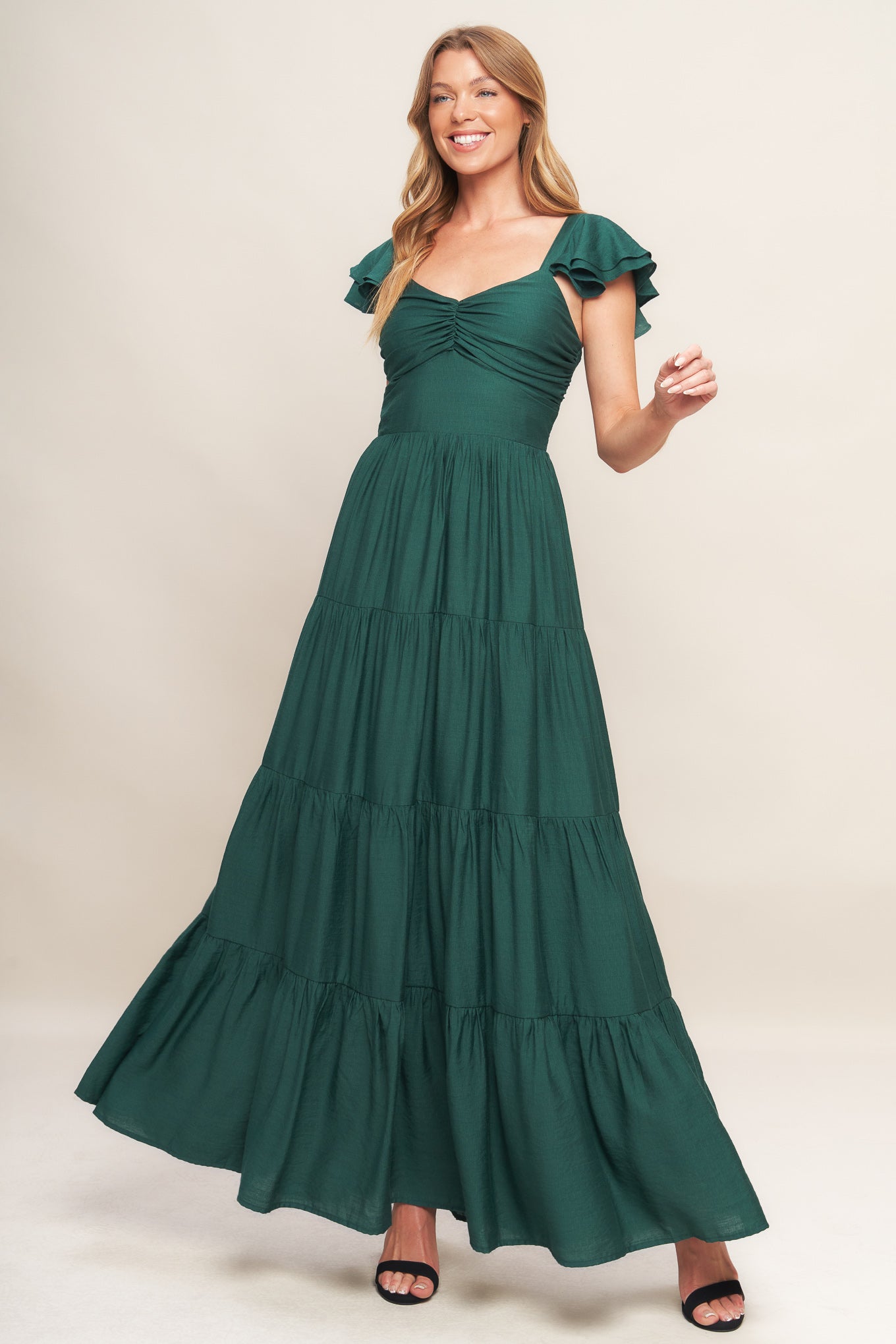 A solid woven maxi dress featuring cami top with layered sleeve, cinched front bodice, tiered skirt and smocked back bodice.
