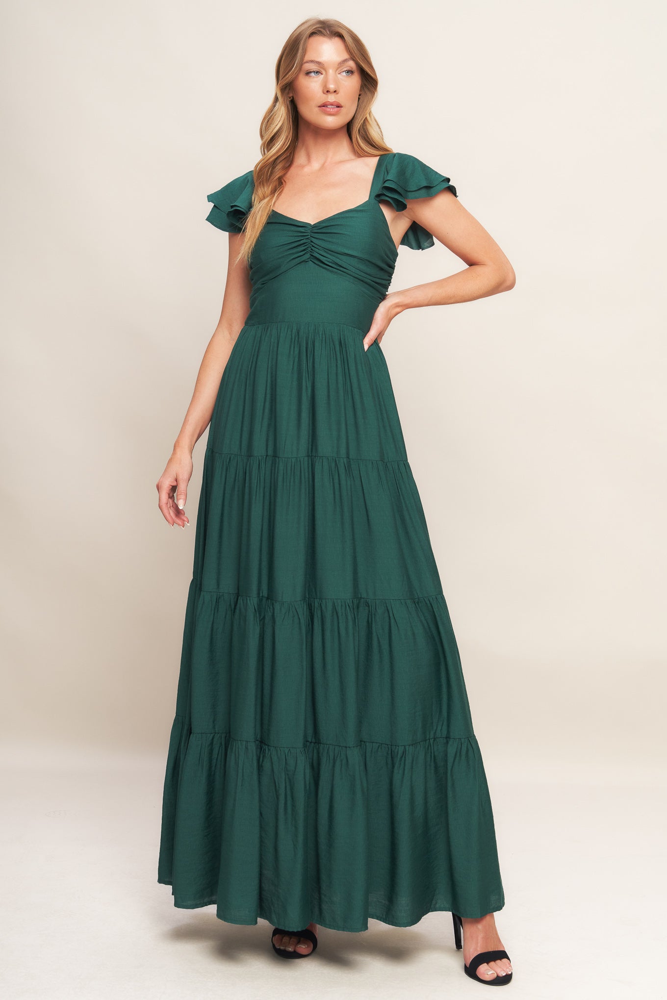 A solid woven maxi dress featuring cami top with layered sleeve, cinched front bodice, tiered skirt and smocked back bodice.