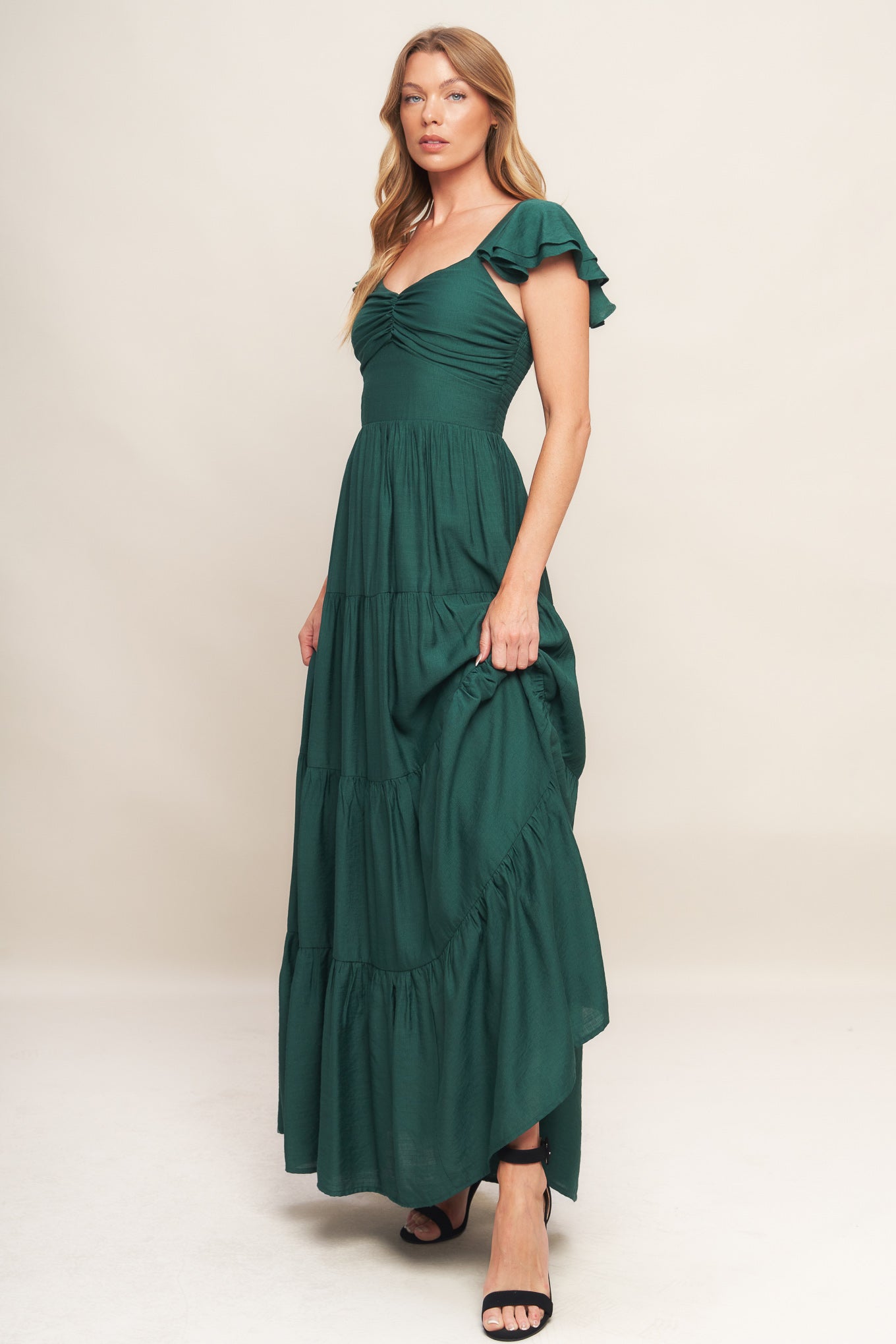 A solid woven maxi dress featuring cami top with layered sleeve, cinched front bodice, tiered skirt and smocked back bodice.