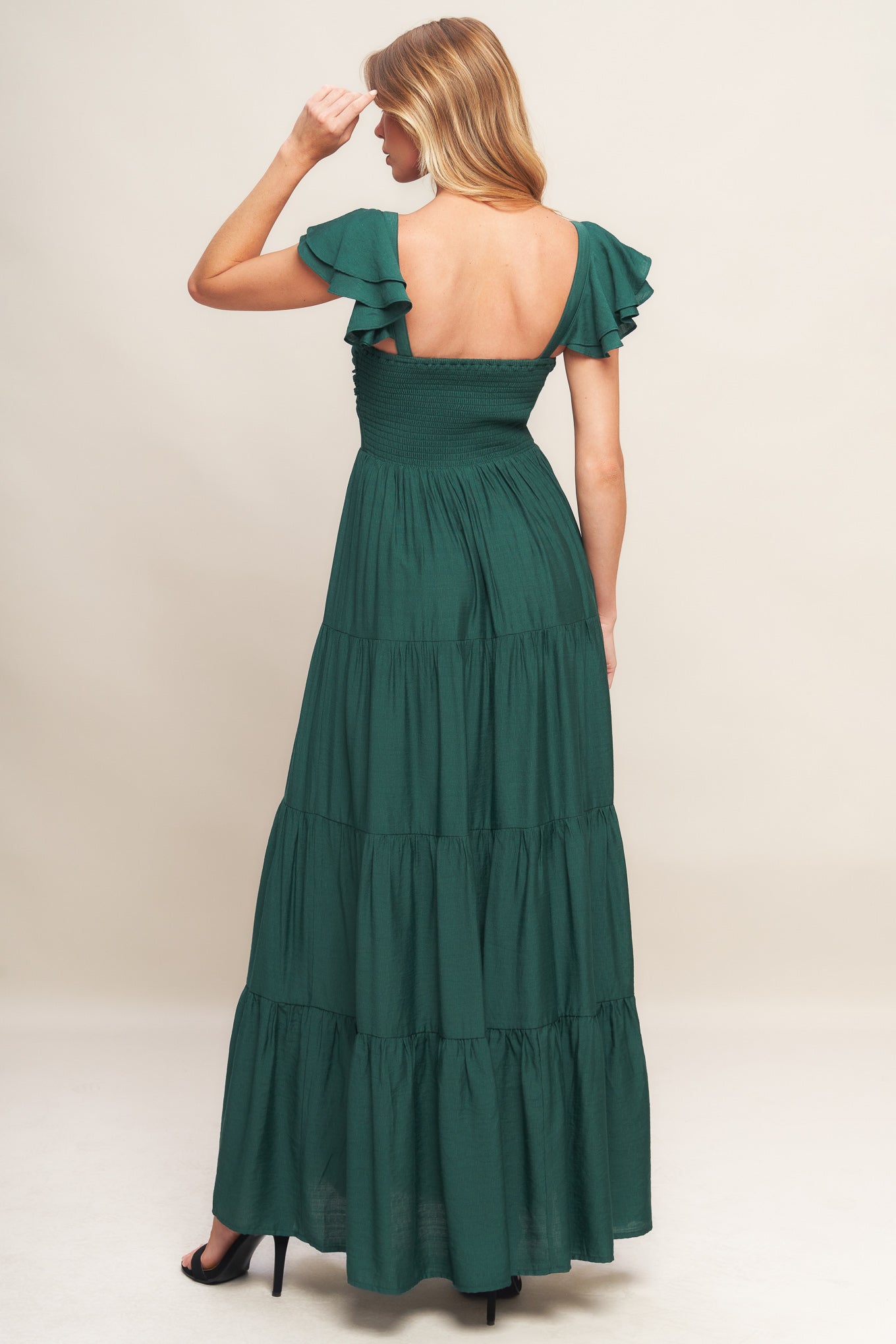 A solid woven maxi dress featuring cami top with layered sleeve, cinched front bodice, tiered skirt and smocked back bodice.
