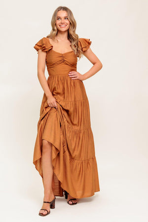 A solid woven maxi dress featuring cami top with layered sleeve, cinched front bodice, tiered skirt and smocked back bodice.