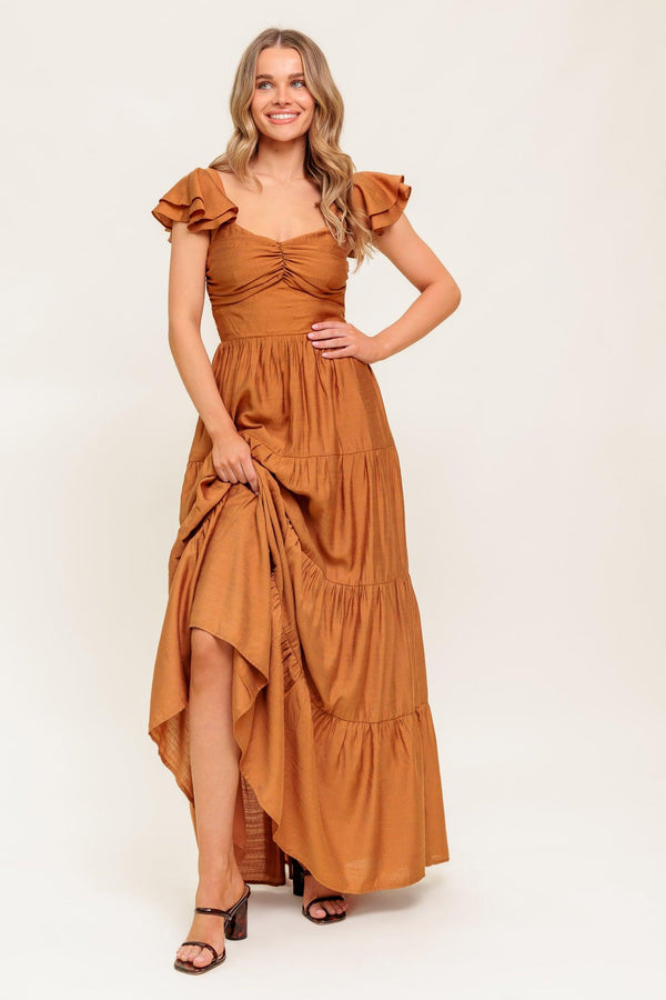 A solid woven maxi dress featuring cami top with layered sleeve, cinched front bodice, tiered skirt and smocked back bodice.