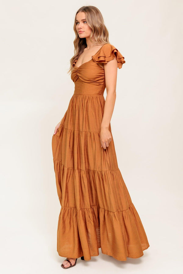 A solid woven maxi dress featuring cami top with layered sleeve, cinched front bodice, tiered skirt and smocked back bodice.