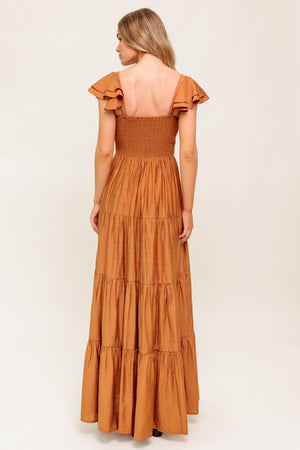 A solid woven maxi dress featuring cami top with layered sleeve, cinched front bodice, tiered skirt and smocked back bodice.