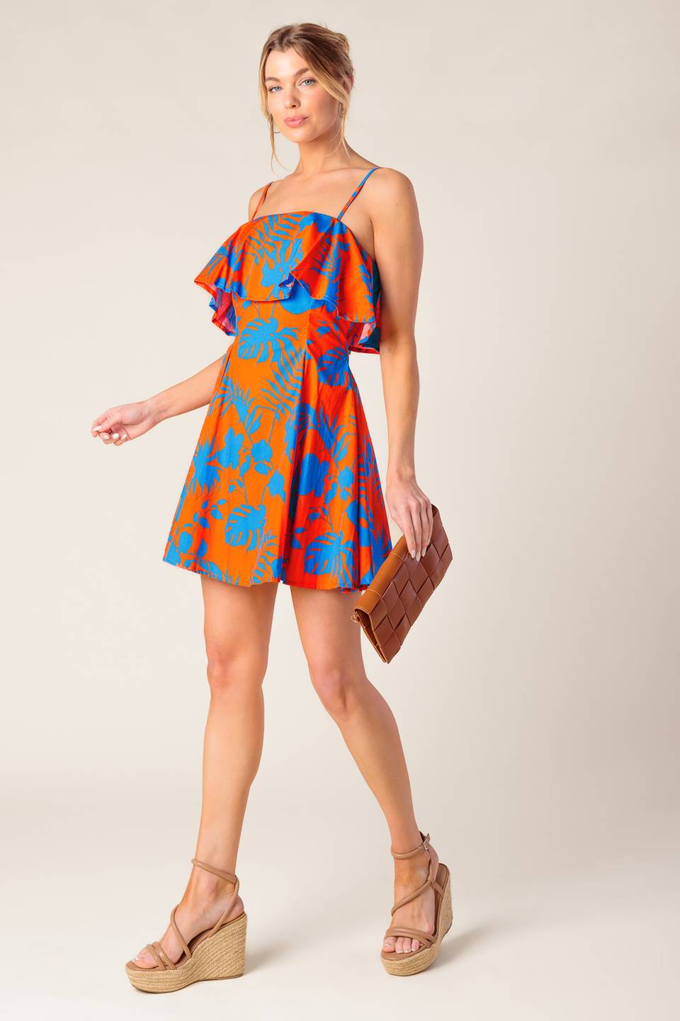 A printed woven mini dress featuring straight neckline, straps, flounce, full skirt and back zipper closure