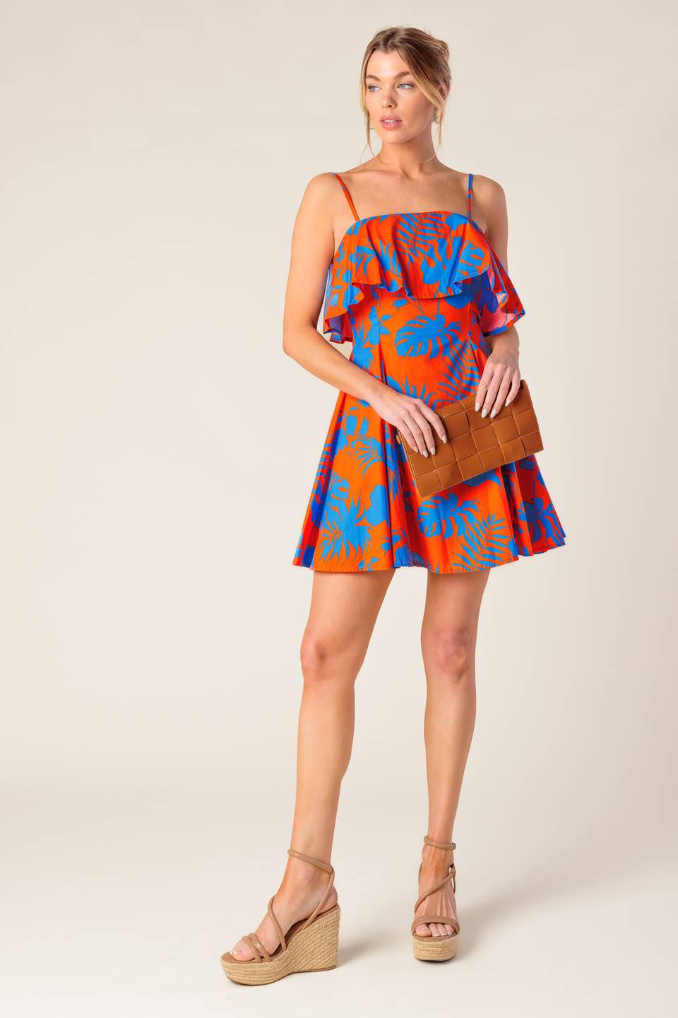 A printed woven mini dress featuring straight neckline, straps, flounce, full skirt and back zipper closure