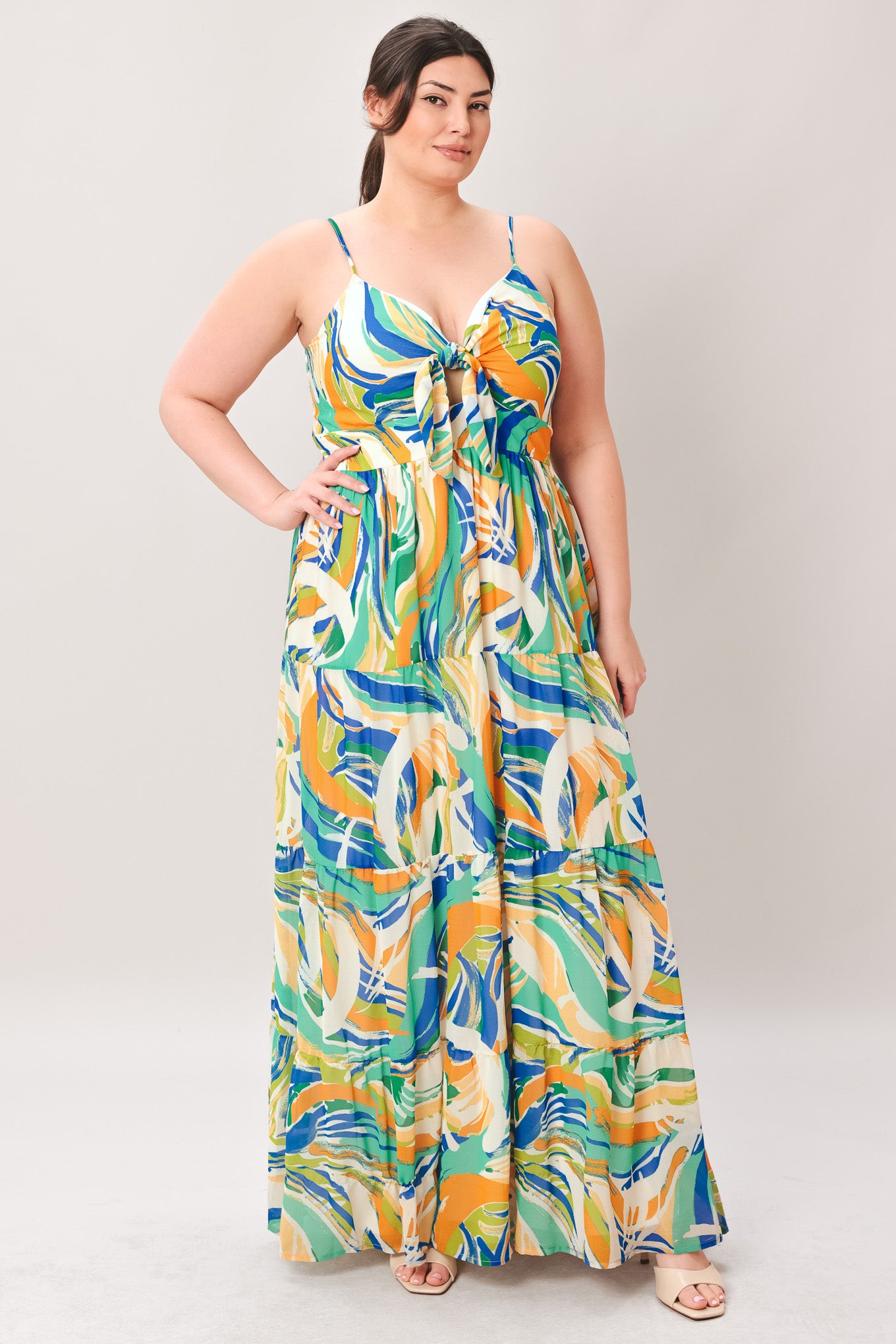 Woman wearing a colorful patterned maxi dress featuring cami bodice with front tie and cut out detail, tiered skirt and smocked back bodice on a plain background | Curve | Flying Tomato