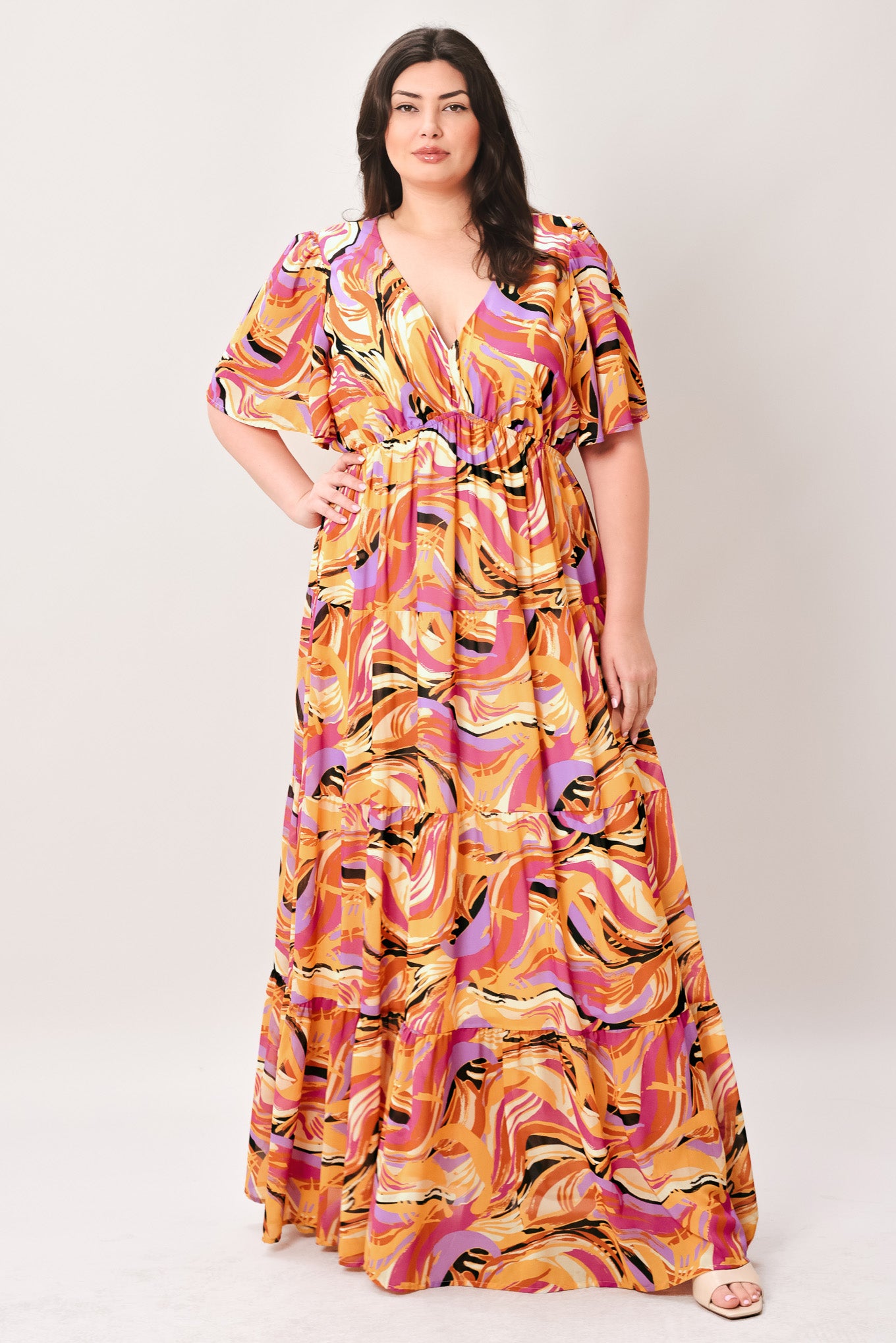 Woman wearing a colorful patterned jumpsuit featuring shirt collar, button down, long sleeve, elasticized waist, self sash tie, side pockets and wide leg on a white background | Flying Tomato
