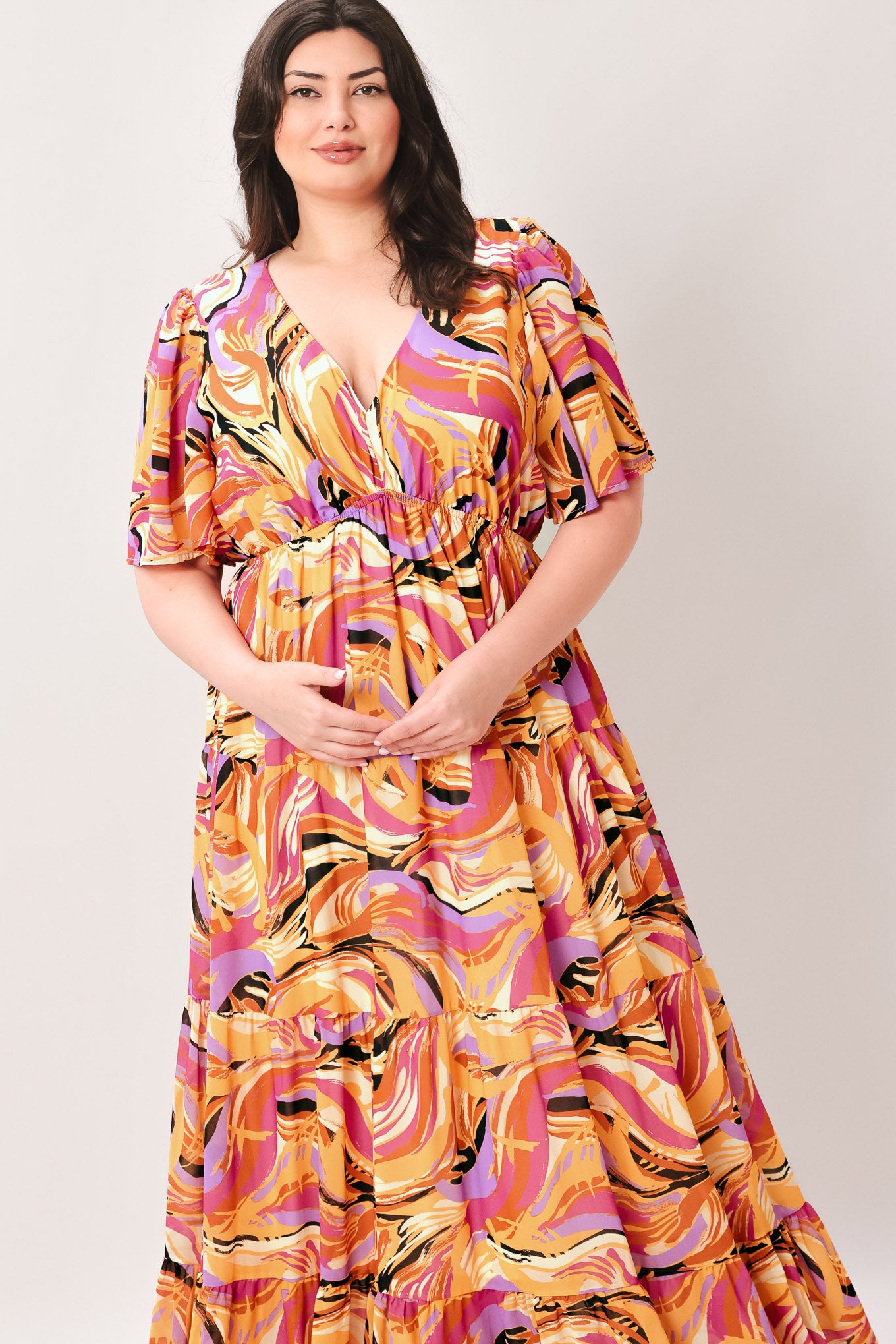 Woman wearing a colorful patterned jumpsuit featuring shirt collar, button down, long sleeve, elasticized waist, self sash tie, side pockets and wide leg on a white background | Flying Tomato