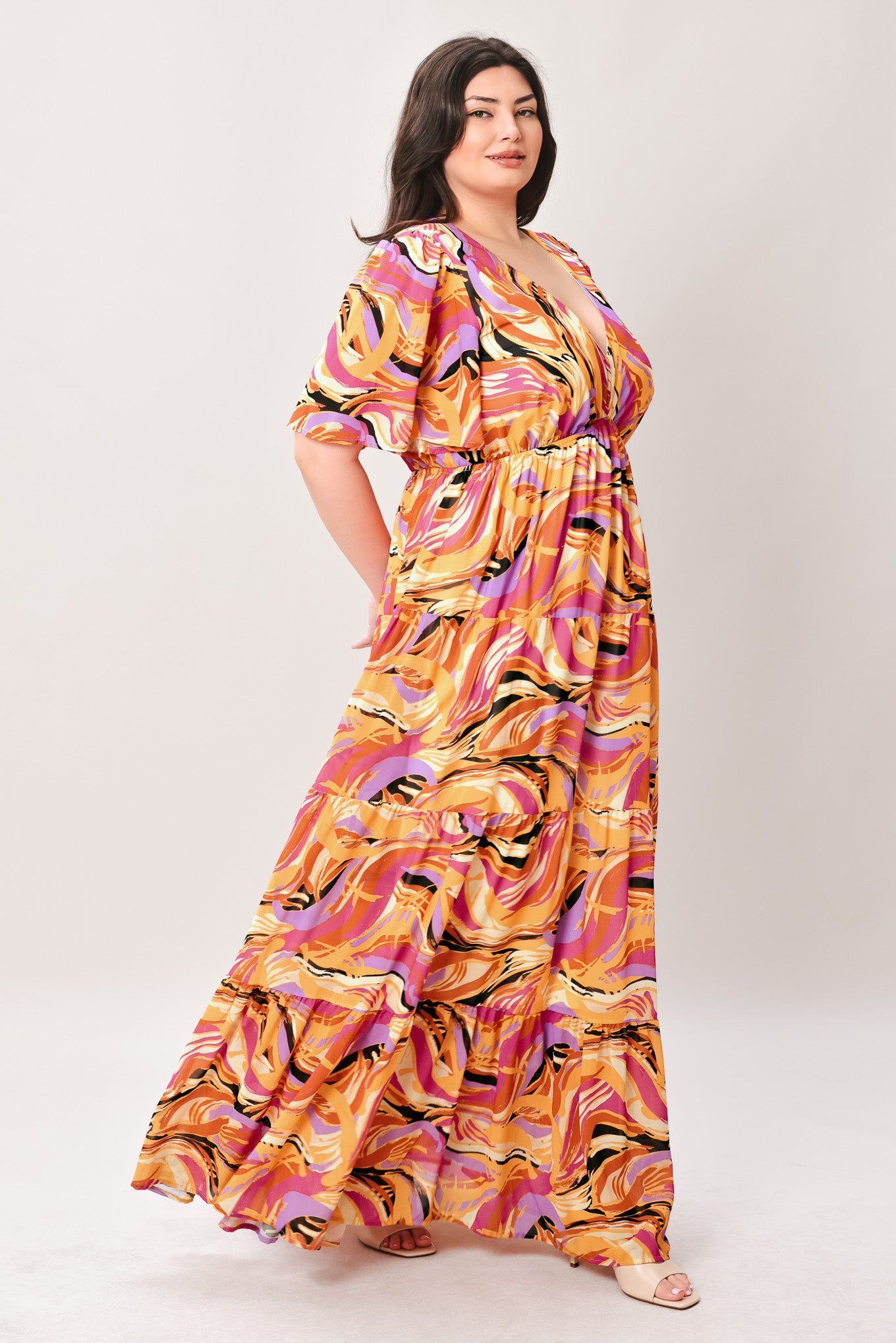 Woman wearing a colorful patterned jumpsuit featuring shirt collar, button down, long sleeve, elasticized waist, self sash tie, side pockets and wide leg on a white background | Flying Tomato