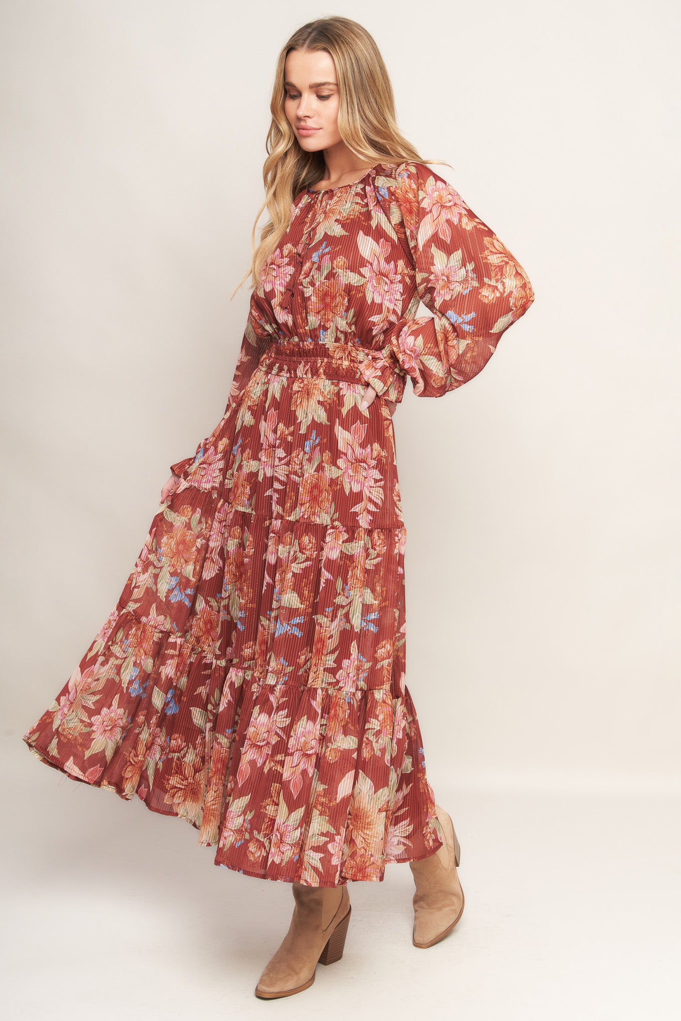 A printed woven midi dress featuring round neckline with front tie, long sleeve, elasticized waist and tiered skirt