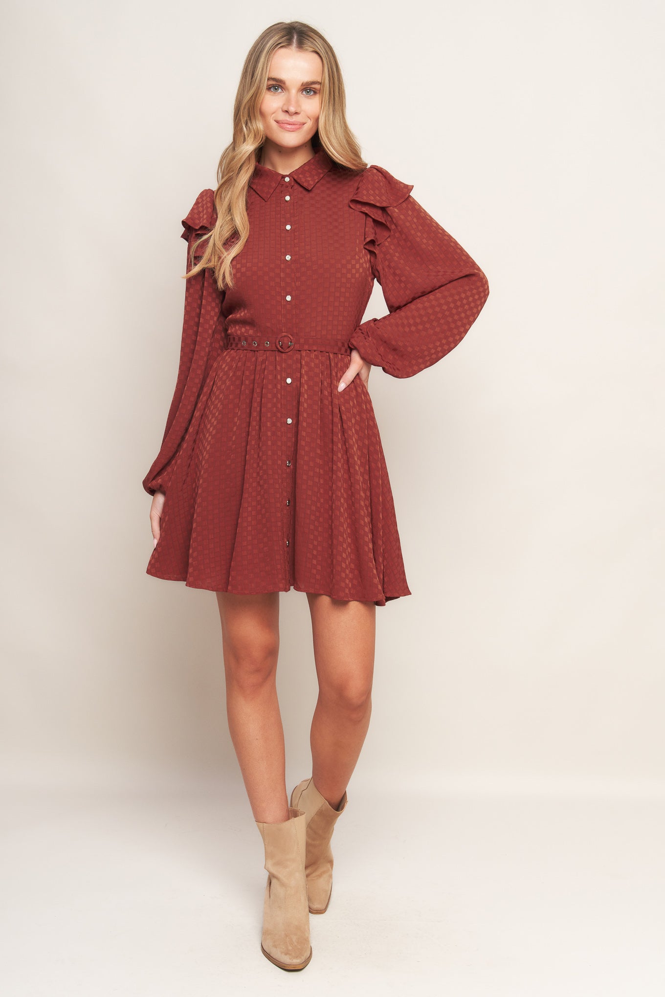 A textured woven mini dress featuring shirt collar, button down, long sleeve with ruffled shoulder, self belt and full skirt
