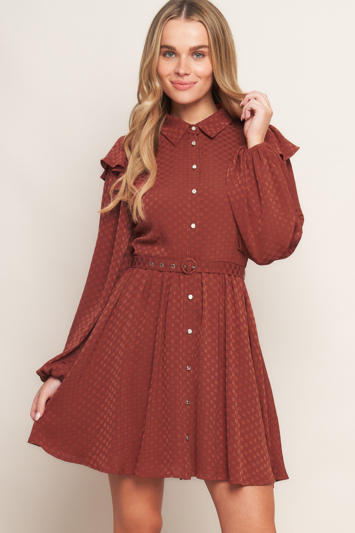 A textured woven mini dress featuring shirt collar, button down, long sleeve with ruffled shoulder, self belt and full skirt