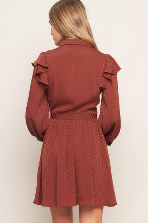 A textured woven mini dress featuring shirt collar, button down, long sleeve with ruffled shoulder, self belt and full skirt