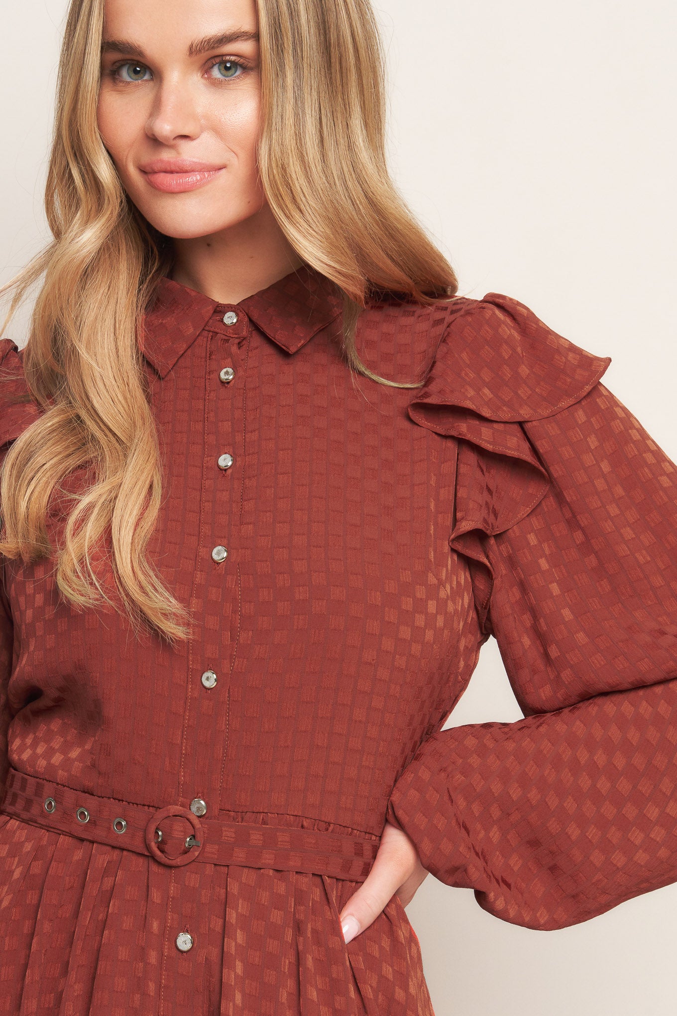 A textured woven mini dress featuring shirt collar, button down, long sleeve with ruffled shoulder, self belt and full skirt