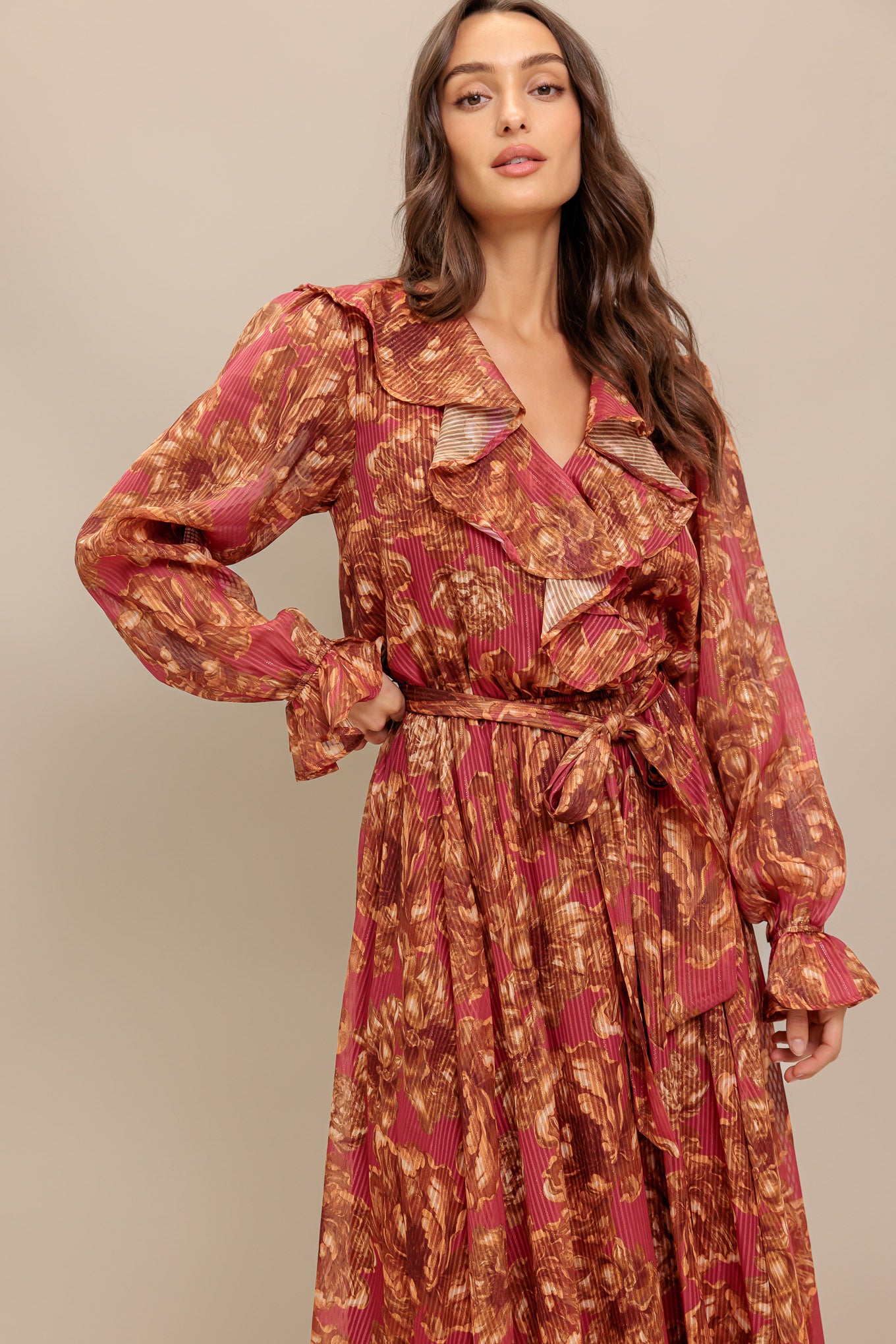 A printed woven midi dress featuring surplice neckline with ruffles, long sleeve with ruffled cuff, elasticized waist with self sash tie and full skirt