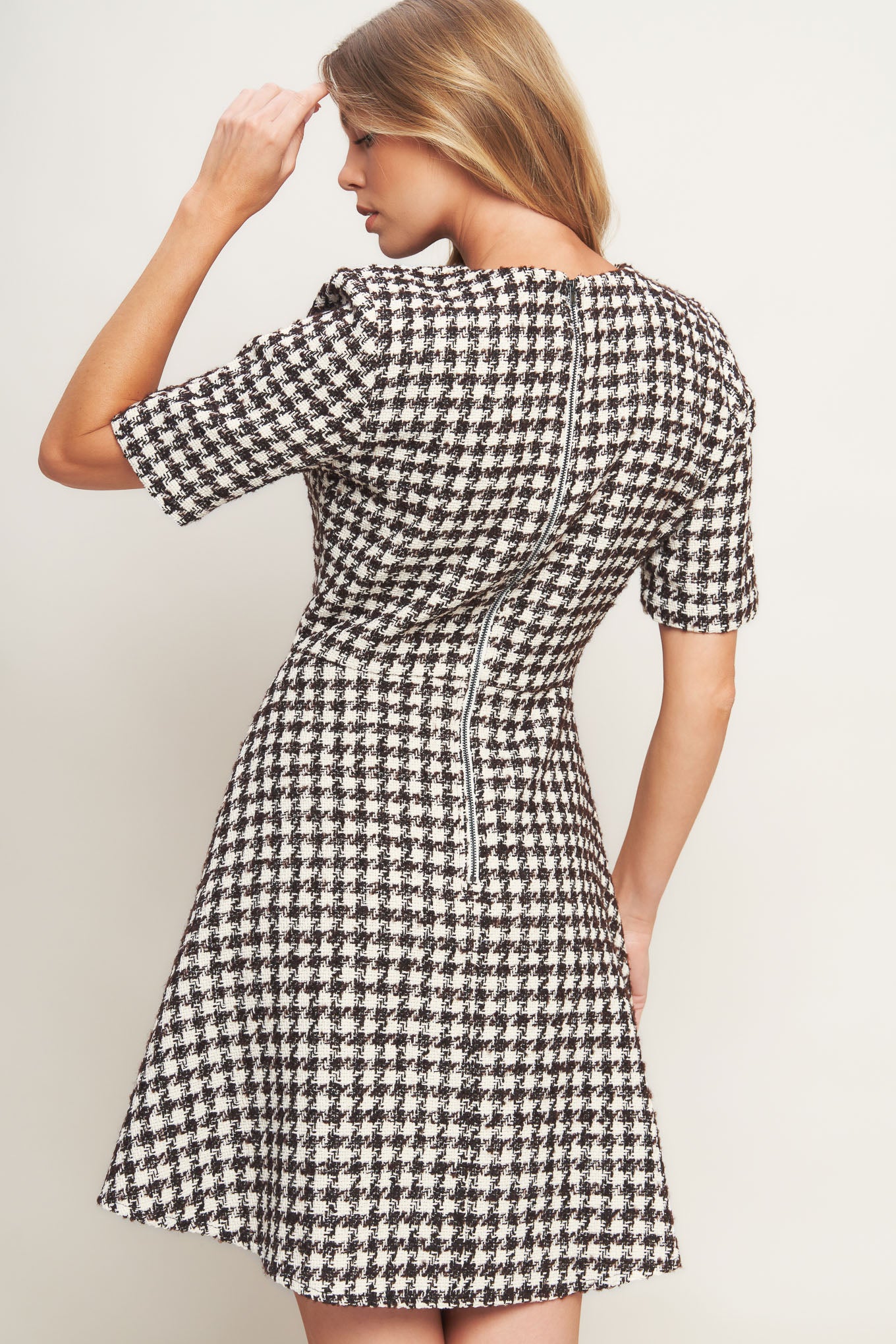 A tweed mini dress featuring round neckline, short sleeve, front button detail, A line skirt and back zipper closure