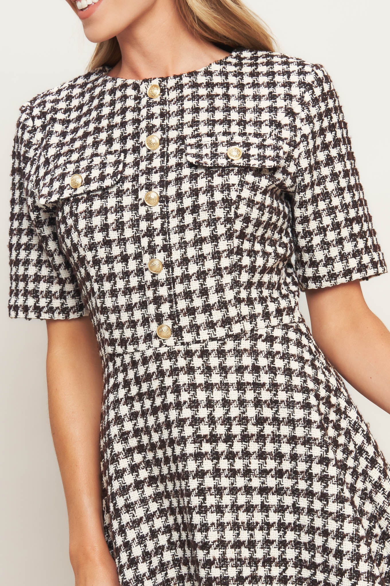 A tweed mini dress featuring round neckline, short sleeve, front button detail, A line skirt and back zipper closure