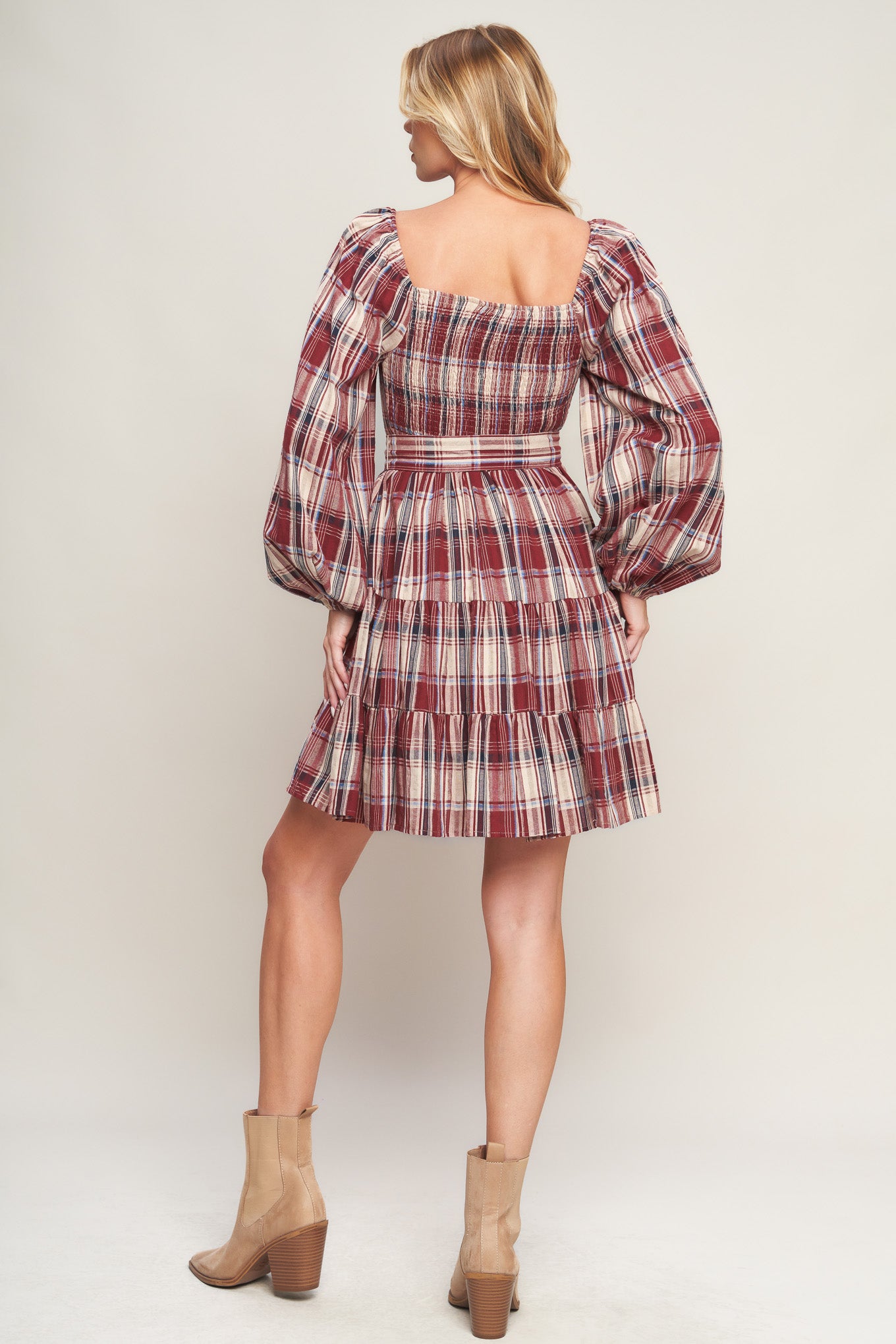 A woven plaid mini dress featuring square neckline, long sleeve, self sash tie, tiered skirt and smocked back bodice
