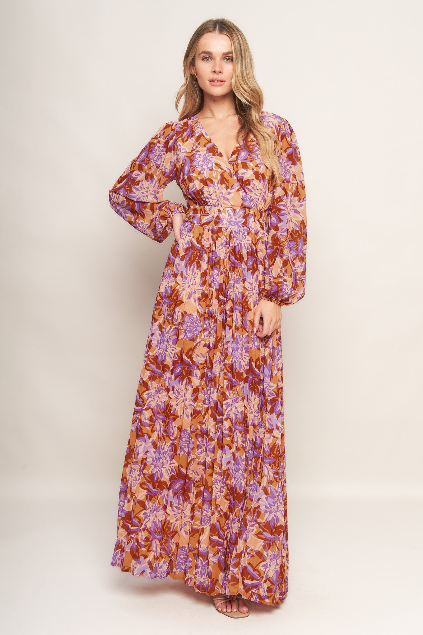 A printed woven maxi dress featuring surplice neckline, long blouson sleeve, pleated skirt and back zipper closure