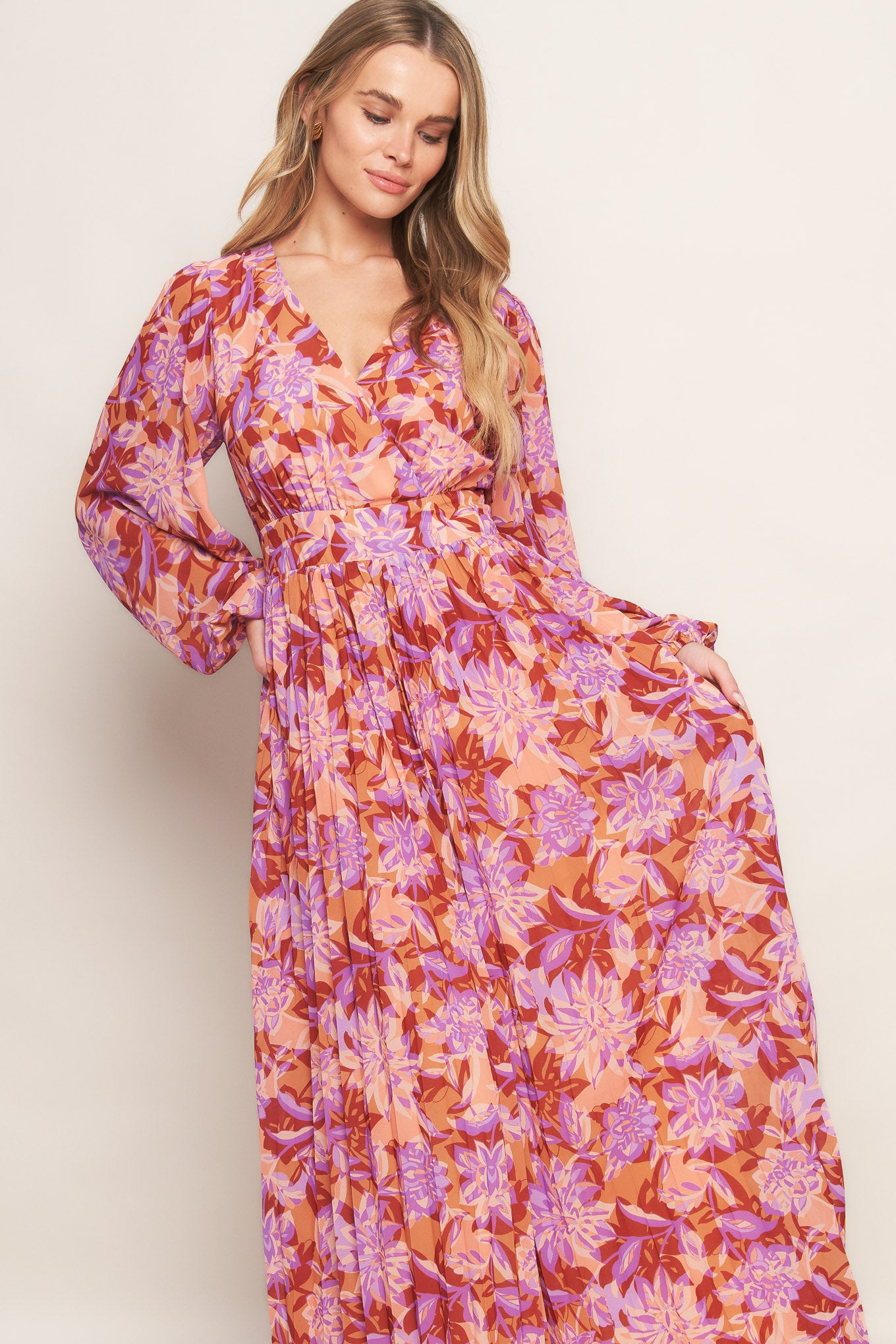 A printed woven maxi dress featuring surplice neckline, long blouson sleeve, pleated skirt and back zipper closure