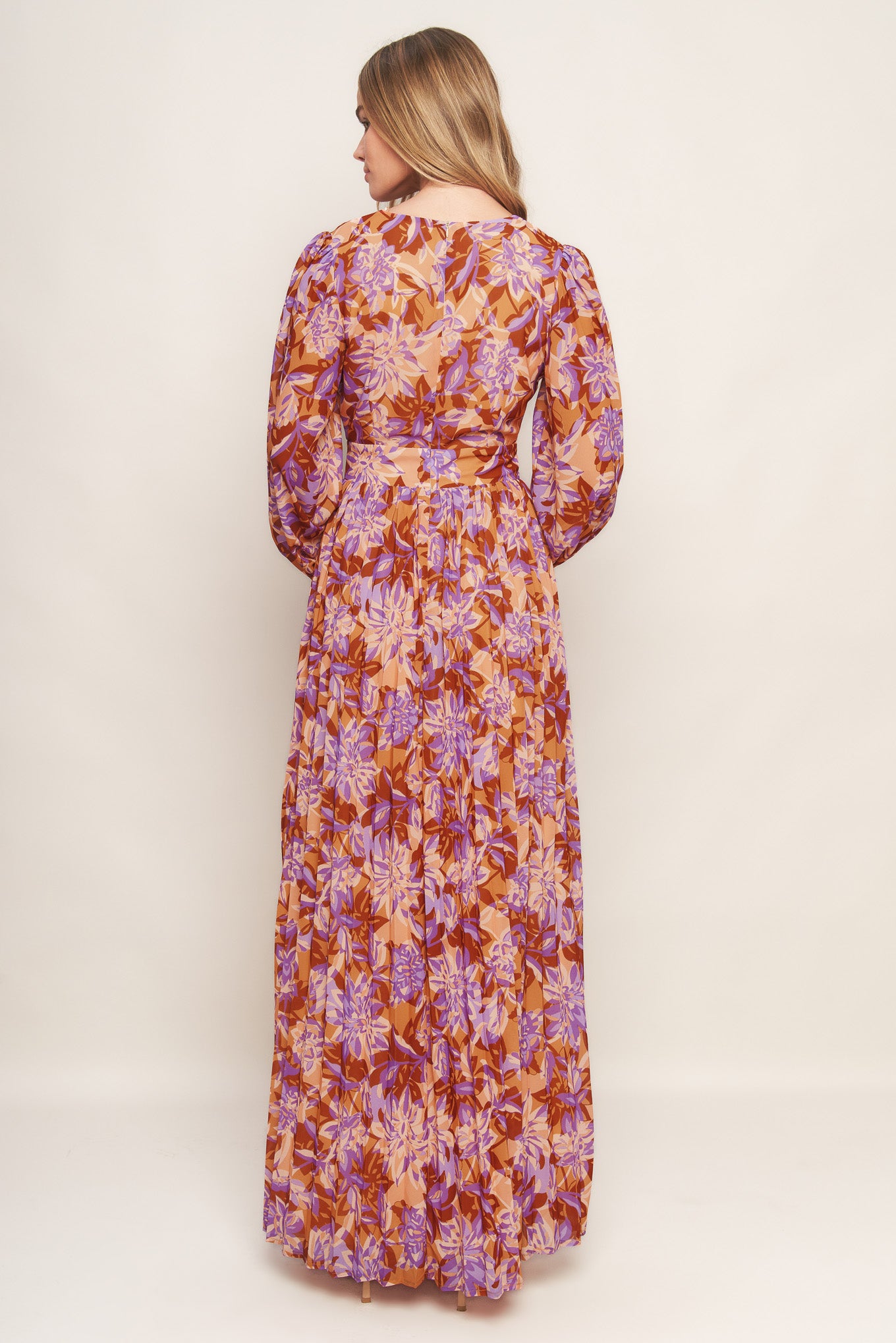 A printed woven maxi dress featuring surplice neckline, long blouson sleeve, pleated skirt and back zipper closure