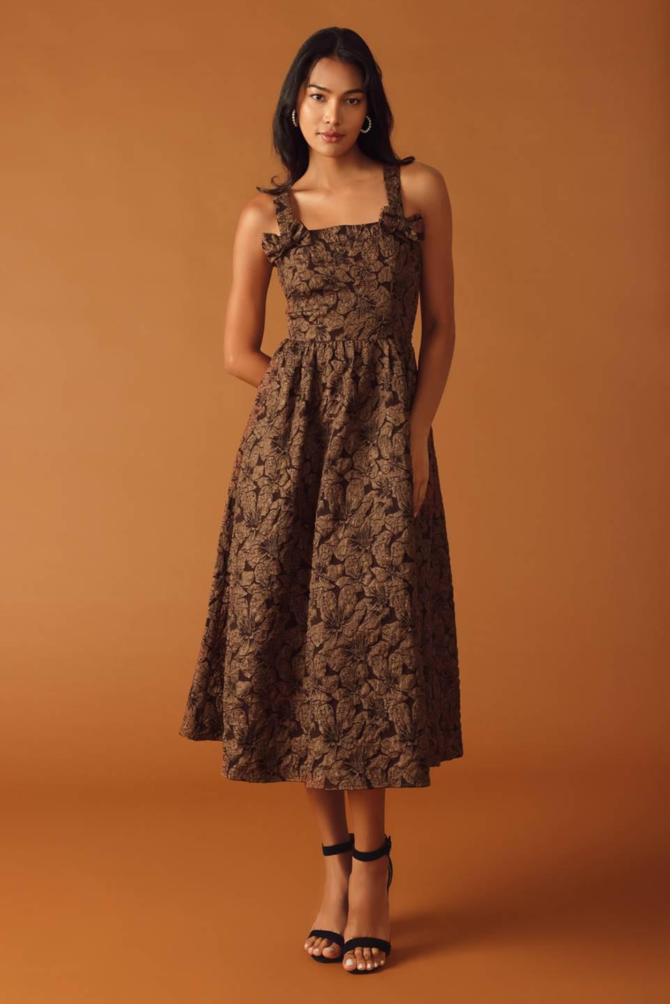 A brown textured woven midi dress featuring straight neckline, strap with bow, full skirt with back zipper closure on a white background | Flying Tomato